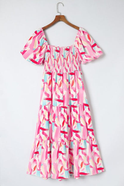 Pink and multicolor patterned dress on a hanger against a white background